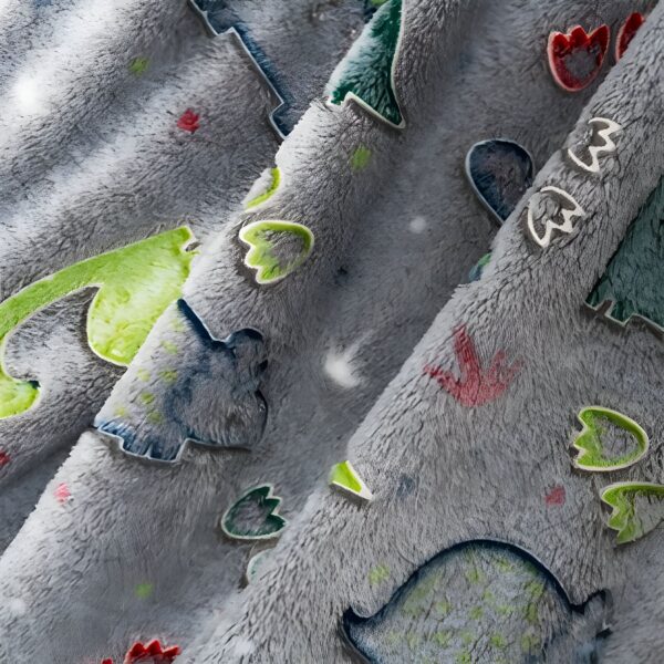 Une couverture en peluche grise avec un motif de dinosaures colorés.