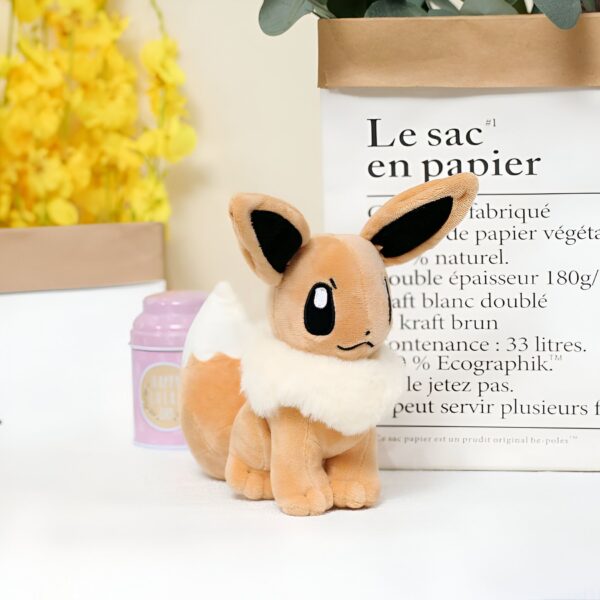 peluche-pokemon-evoli-et-aquali-pack-de-2-2a-2 Peluche Eevee marron et blanc assis sur une table blanche.