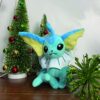 peluche-pokemon-evoli-et-aquali-pack-de-2-3a-1 Une peluche de Vaporeon, un Pokémon de type Eau, assis près de deux arbres de Noël décorés de boules rouges et dorées.