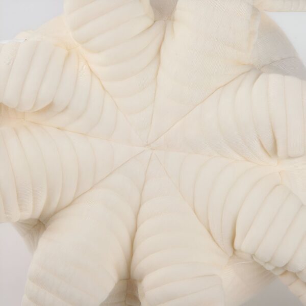 Un coussin en forme d'étoile de mer en tissu crème avec une texture plissée.