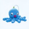 Une pieuvre bleue en crochet avec des yeux noirs et une bouche rouge.