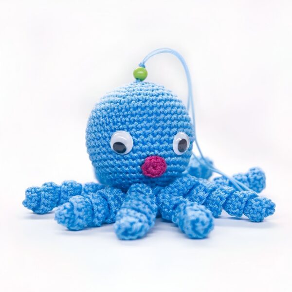 Une pieuvre bleue en crochet avec des yeux blancs et une bouche rose.