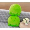 Deux adorables peluches poulpes verts empilées sur un canapé gris à carreaux.