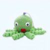 Une pieuvre en crochet vert avec de grands yeux et une bouche rouge.