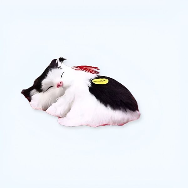 Un chat noir et blanc en peluche endormi sur le dos.