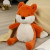 Peluche renard orange et blanc assis sur un fond beige.