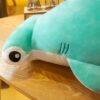 Une peluche de requin marteau turquoise sur un fond en bois.