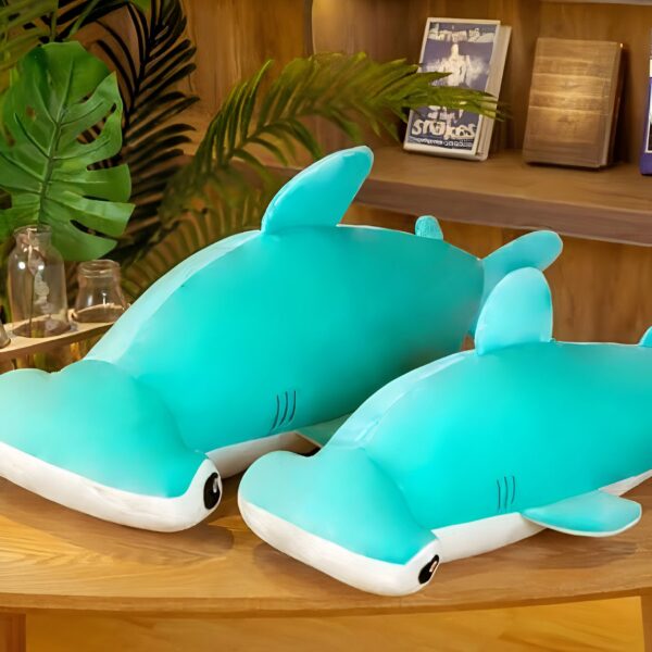 Deux peluches en forme de requin-marteau bleu clair sont posées sur une table en bois.