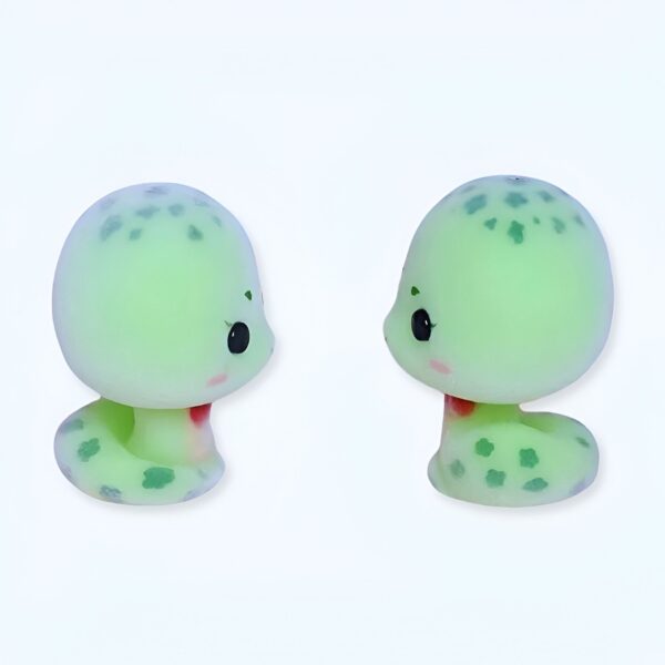 Deux petits serpents verts mignons en plastique avec des yeux noirs et des joues rouges se font face.