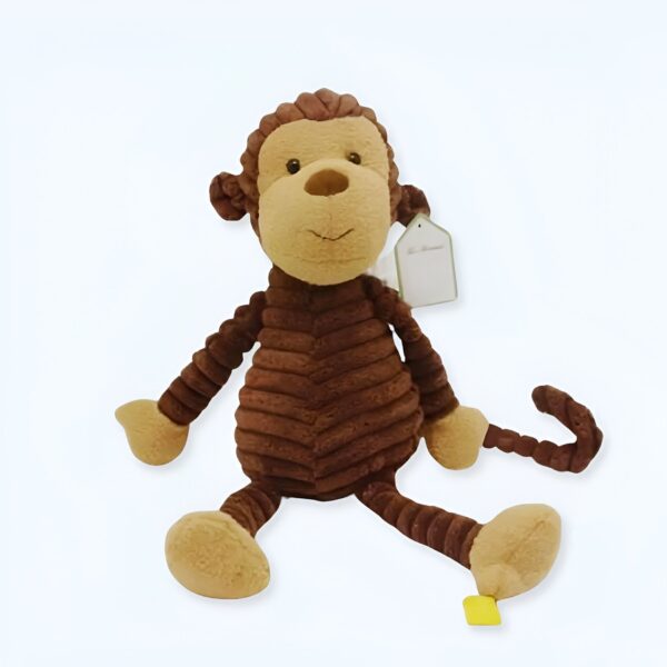 Une peluche de singe marron avec un visage beige souriant, assis sur un fond blanc.