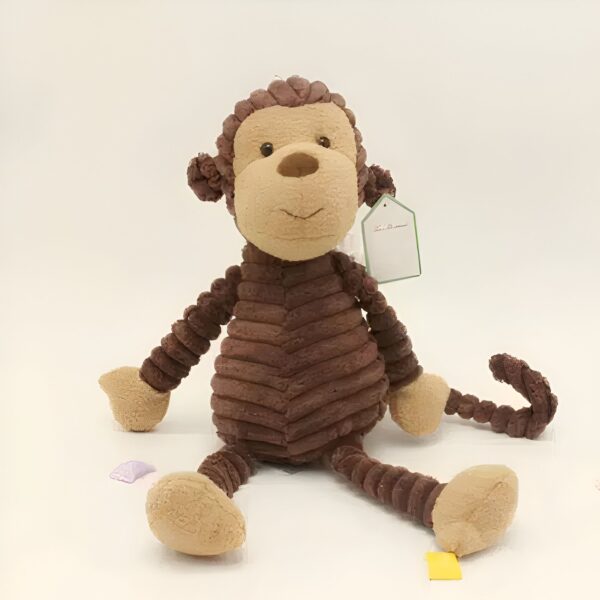 Une peluche singe marron assis avec une étiquette sur son bras.