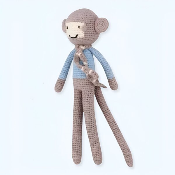 Un singe en tricot beige avec un haut bleu et une écharpe.