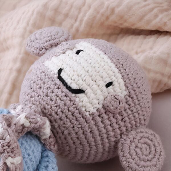 peluche-singe-tricot-jouet-en-peluche-tricote-de-haute-qualite-cadeau-pour-enfants-2a-2 Un singe en tricot rose avec un sourire brodé, reposant sur une couverture en coton doux.