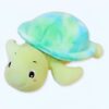 Une tortue en peluche verte avec une carapace bleue et verte. La tortue a un visage souriant avec de grands yeux.