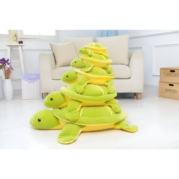 Une pile de quatre tortues en peluche de différentes tailles, empilées les unes sur les autres. Les tortues sont vertes et jaunes avec des yeux noirs et souriants.