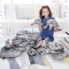 Une jeune femme souriante tenant des peluches de tortues marines. Elle est assise sur un canapé blanc avec un coussin à carreaux et un tapis rayé.