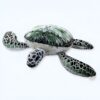 peluche-tortue-de-mer-verte-jouet-calin-pour-enfants-oreiller-doux-1a Une tortue en peluche verte et blanche allongée sur le dos.