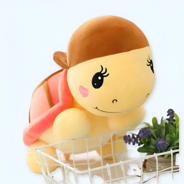 Une peluche de tortue jaune avec une coquille rose et des cils. La tortue est dans un panier en métal.