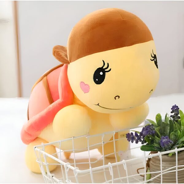 Une tortue en peluche jaune avec une coquille rose et un bandeau marron.