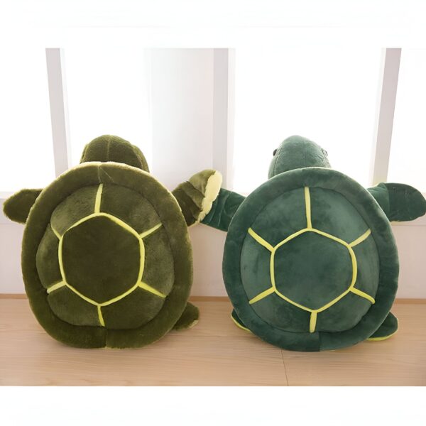 Deux tortues en peluche vertes avec des coquilles jaunes. Les tortues sont posées sur un plancher en bois.