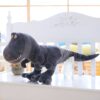 Une peluche de dinosaure gris assis sur un banc blanc.