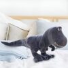 Un grand dinosaure en peluche gris sur un lit blanc avec des oreillers.