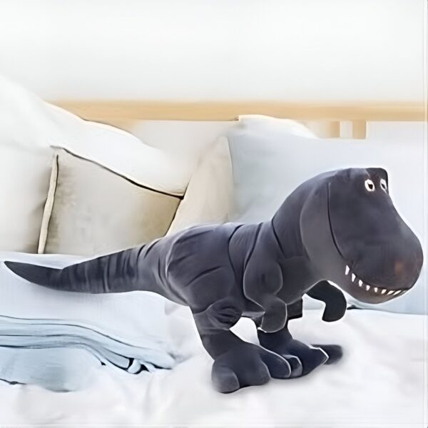 Un grand dinosaure en peluche gris sur un lit blanc avec des oreillers.