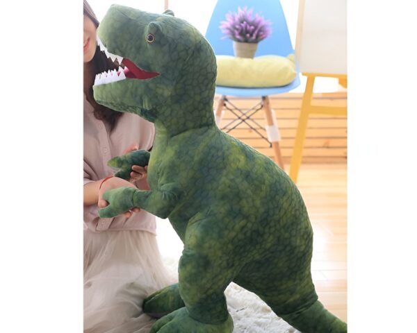 Une peluche de dinosaure vert de grande taille avec une femme en arrière-plan.