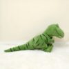 Un gros dinosaure vert en peluche allongé sur un tapis blanc.