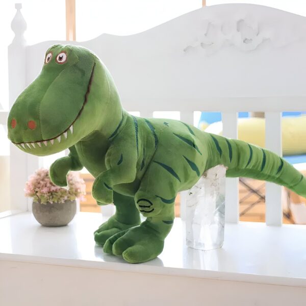 Une peluche verte de dinosaure Tyrannosaure Rex, avec des yeux noirs et une bouche ouverte, se tient sur un banc blanc.