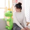 Une jeune femme souriante assise sur un canapé avec un gros dinosaure en peluche vert.
