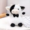 Une peluche vache blanche et noire avec un nœud papillon noir.