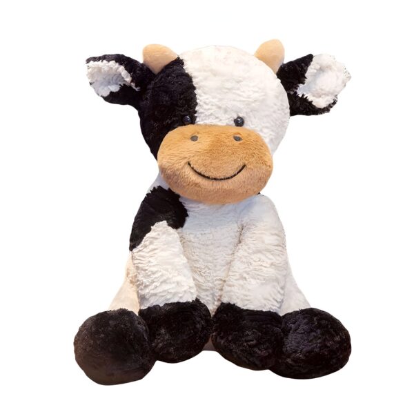 Une vache en peluche noire et blanche avec un sourire est assise sur un fond blanc.
