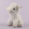 Une peluche blanche de vache Highland, assise sur un fond violet.