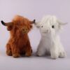 Deux peluches de vache Highland, une brune et une blanche, assis sur un fond blanc.