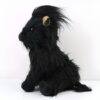 Peluche noire assise avec de longs poils noirs, une petite oreille beige visible et des yeux noirs.