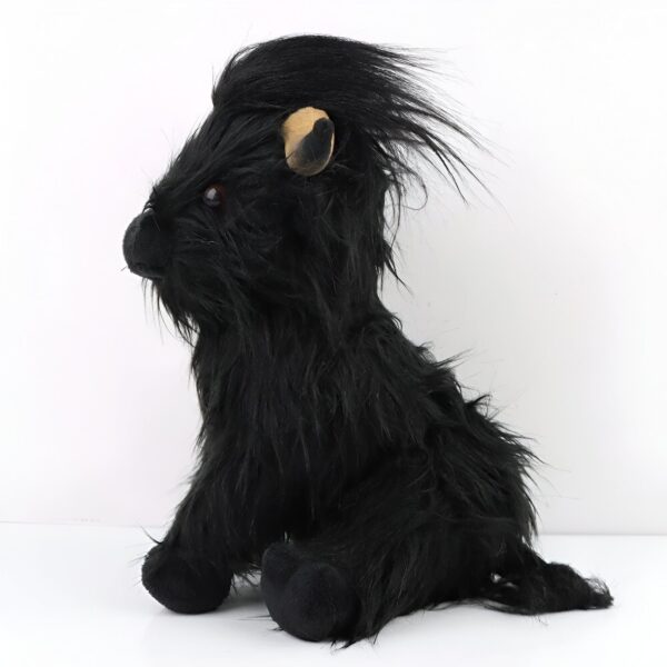 Peluche noire assise avec de longs poils noirs, une petite oreille beige visible et des yeux noirs.