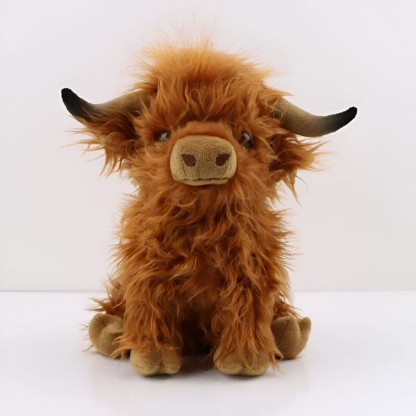 Une peluche brune et poilue en forme de vache écossaise assise sur un fond blanc.