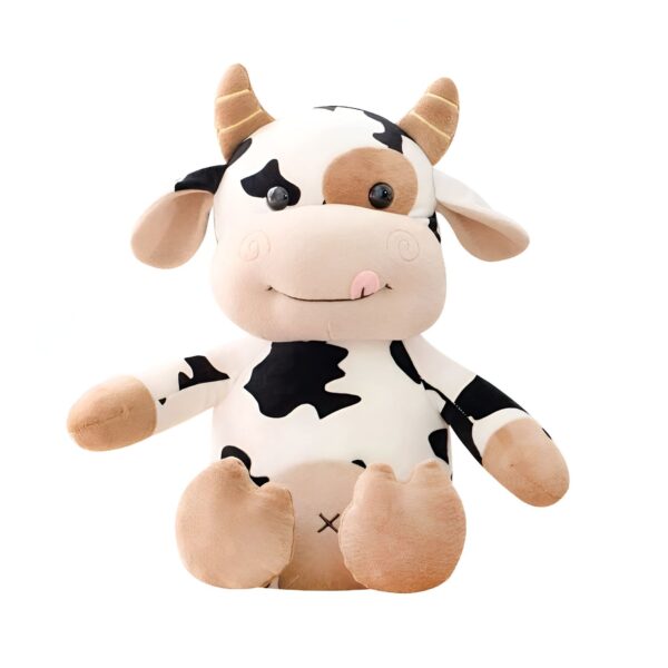 Une peluche de vache blanche et noire avec des yeux noirs et une langue rose qui sort. Elle est assise sur un fond blanc.