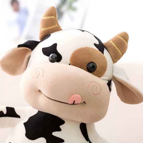 Une vache en peluche avec des yeux noirs, une langue rose et des taches noires et blanches.