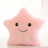 Coussin en forme d'étoile rose avec un visage souriant et une lumière intégrée.