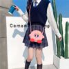 Une jeune femme portant une jupe à carreaux et un sac à main en forme de personnage de dessin animé rose.