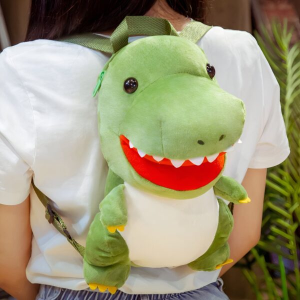 Un sac à dos en peluche en forme de dinosaure vert avec des dents pointues et une bouche rouge. Le sac à dos est porté par une personne.